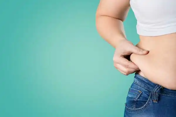 Image of woman pinching her love handles to show weight gain Blandford Forum